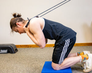 kneeling crunch on a balance pad demonstrated by a young male