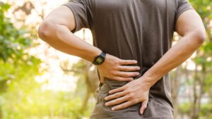 man with hands on lower back wearing a watch