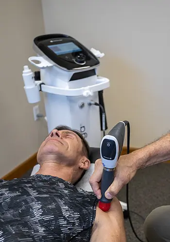 A photo of a patient receiving Radial Pressure Wave Therapy on their left shoulder.